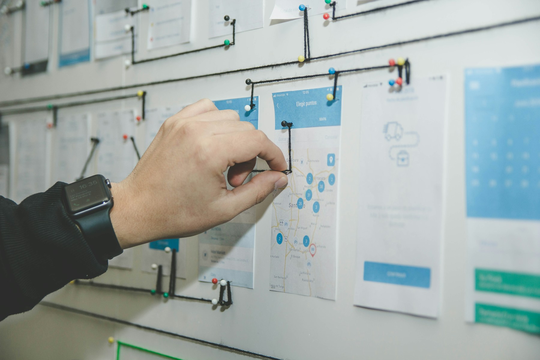 A hand pointing at web flow documents on a wall